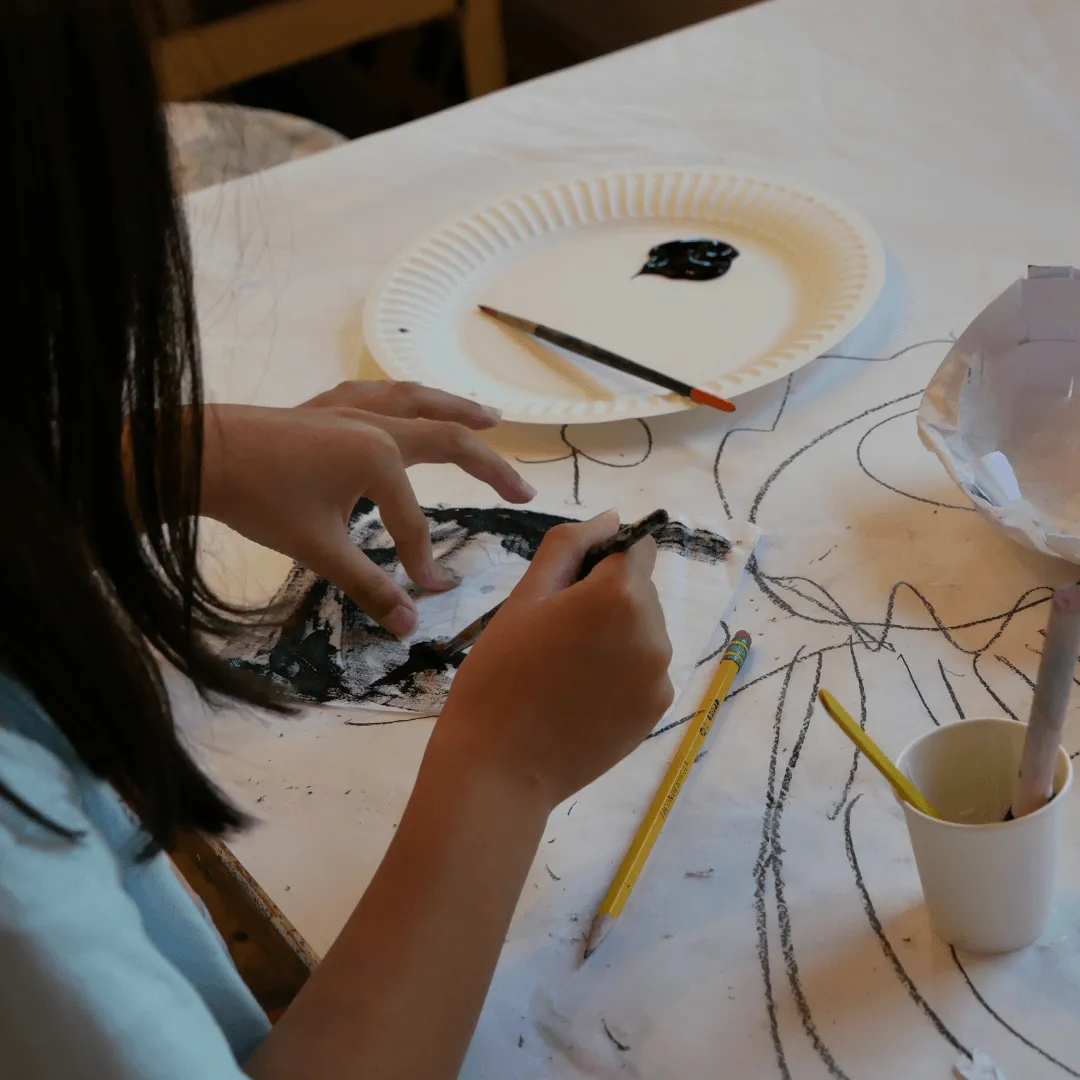 Art student paints images on a paper covered art table at River Gallery School of Art