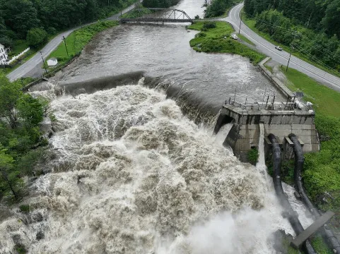 Overview look of a dam. Water overflowing and aggressively flowing out. 