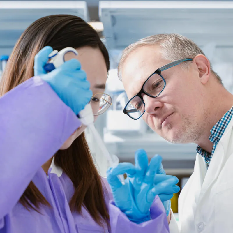 two people in a lab looking at a test tube