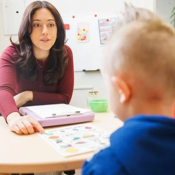 Student working with a young client in a SLP therapy room