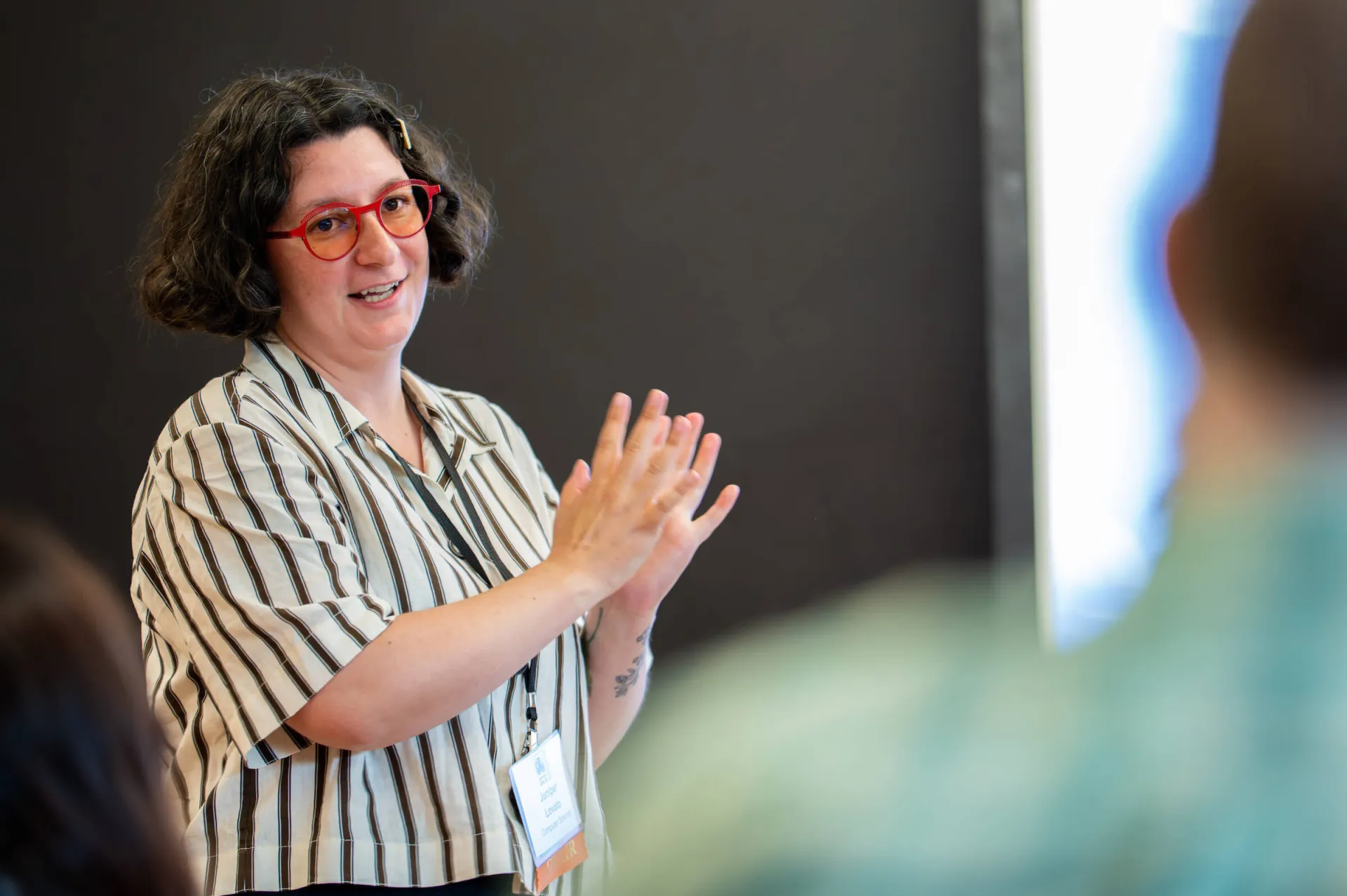Juniper Lavato speaks in front of a group of people attending a conference