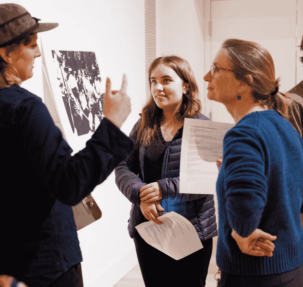 Two students discuss an artwork with a faculty member in the Fleming's Learning Studio.