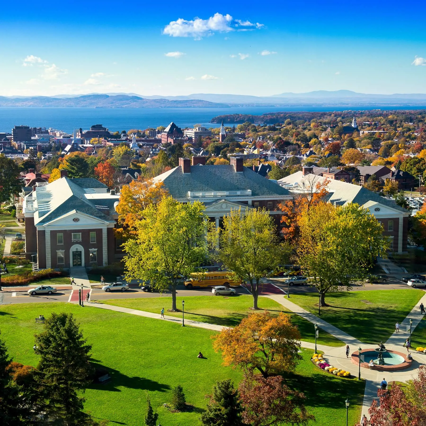 An aerial shot of the university green in autumn, the lake and mountains in the background.