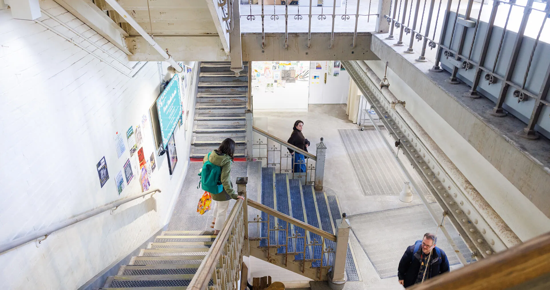 Students walking through an art building stairwell.