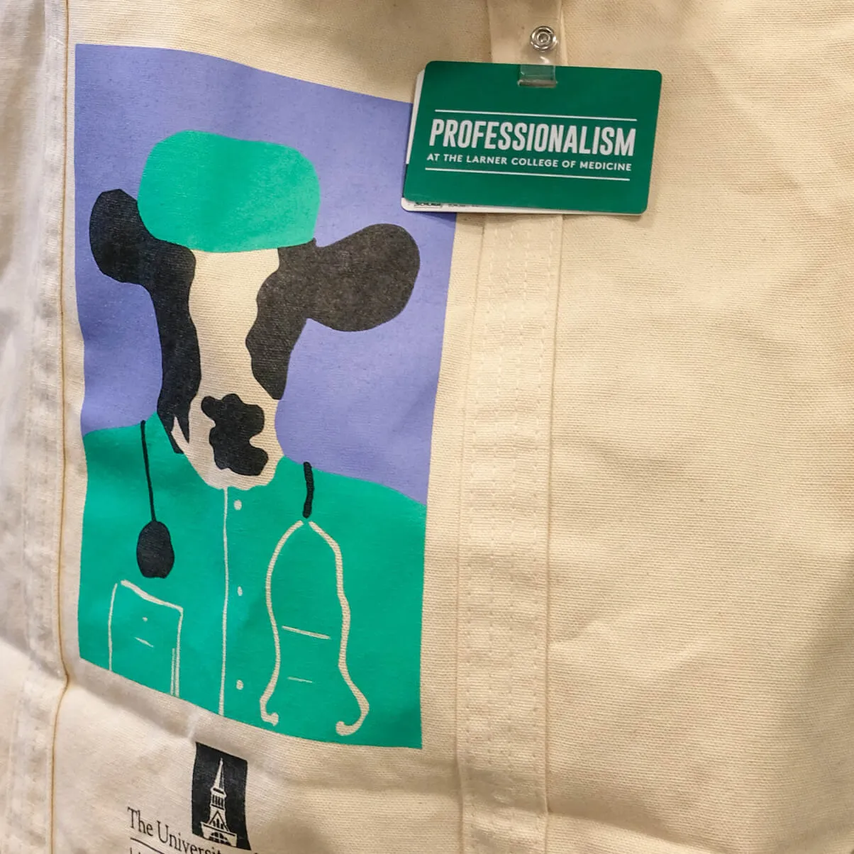 Tote bag with cartoon painting of a cow in a surgical outfit and a staff badge that says "Professionalism"