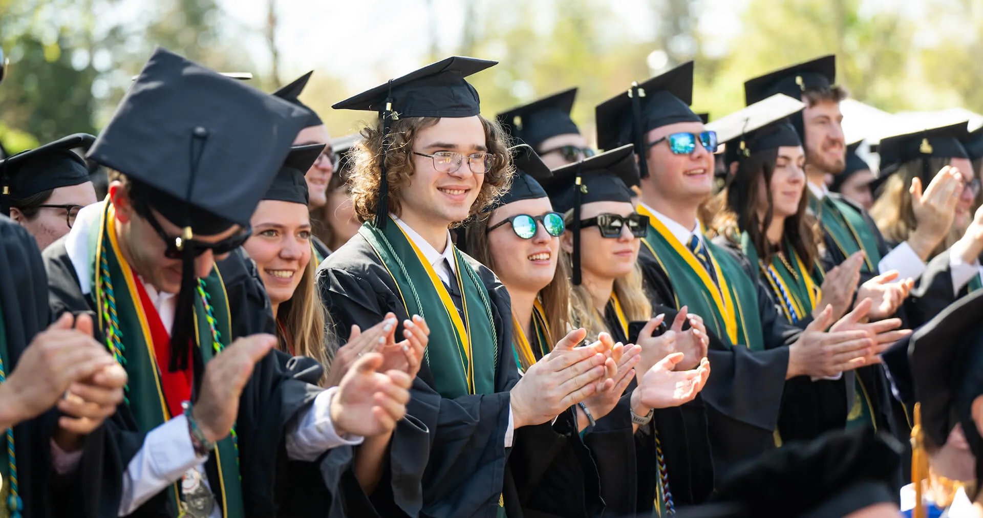 UVM graduates applauding at commencement.