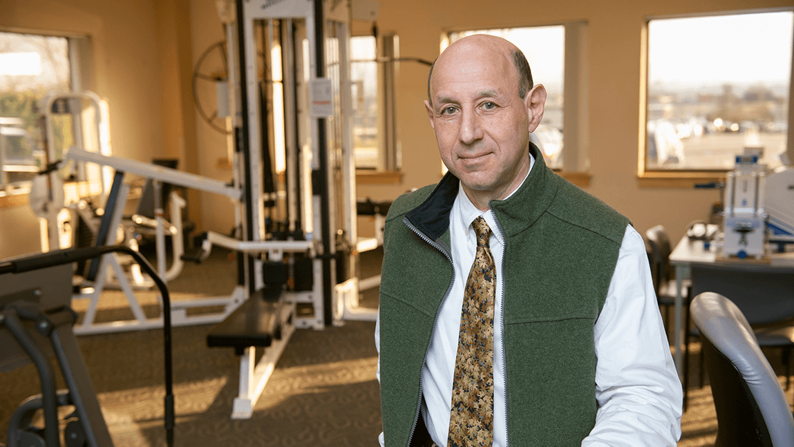 a man standing with cardiac rehab equipment in the background