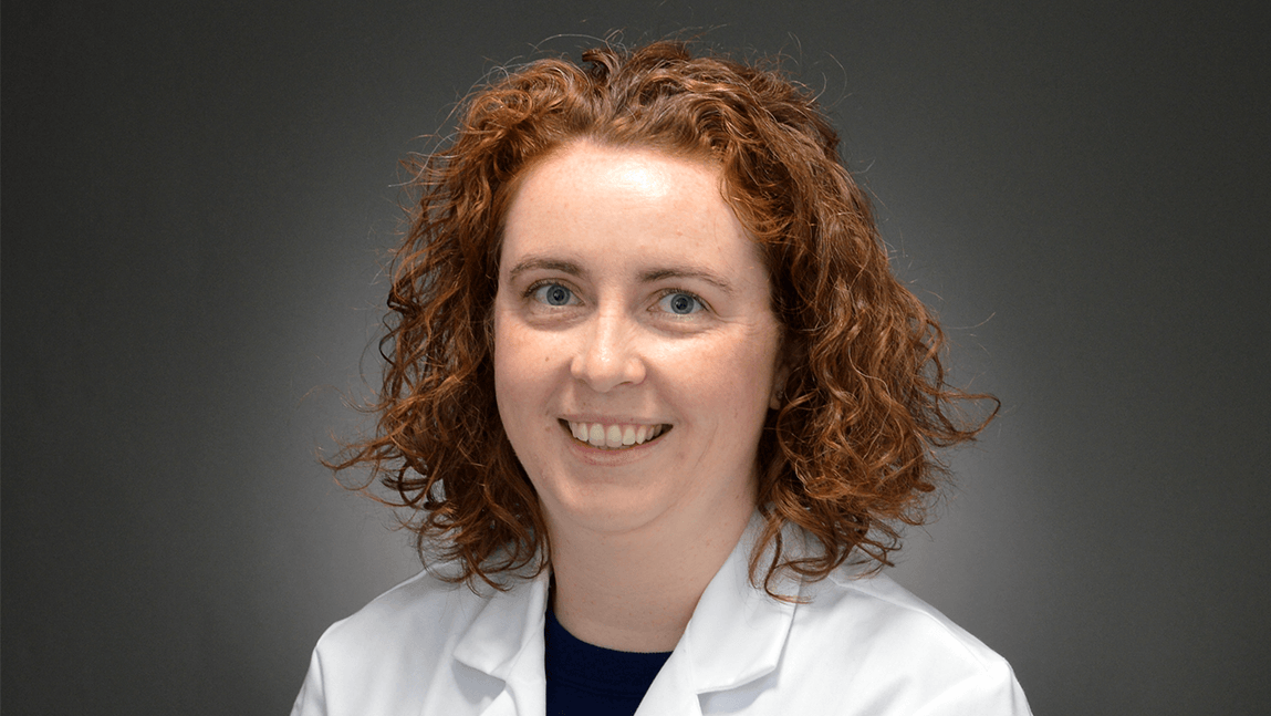 a smiling woman in a white doctor's coat