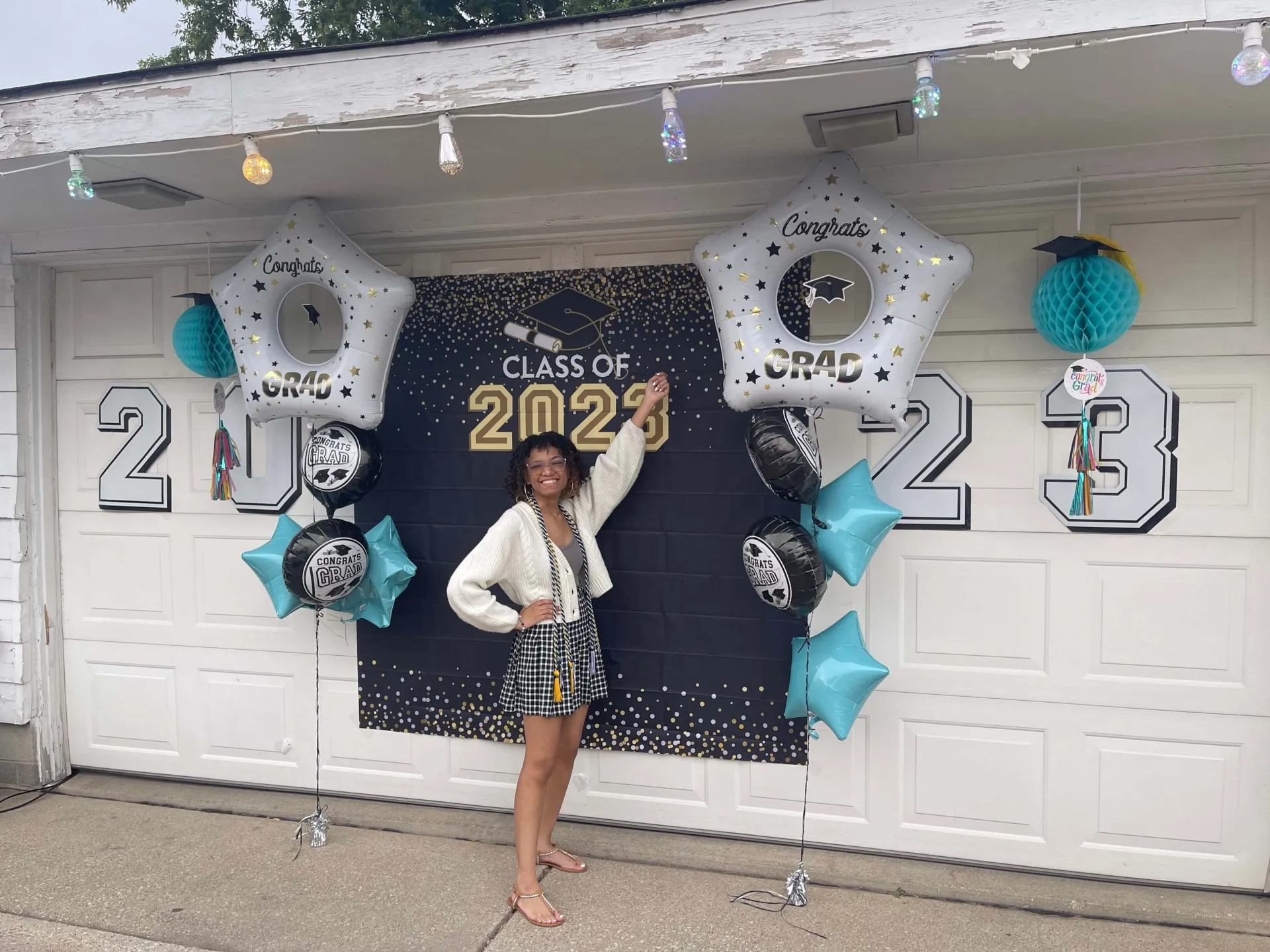 Recent first-gen graduate Nerida Williams celebrating graduation by her garage door