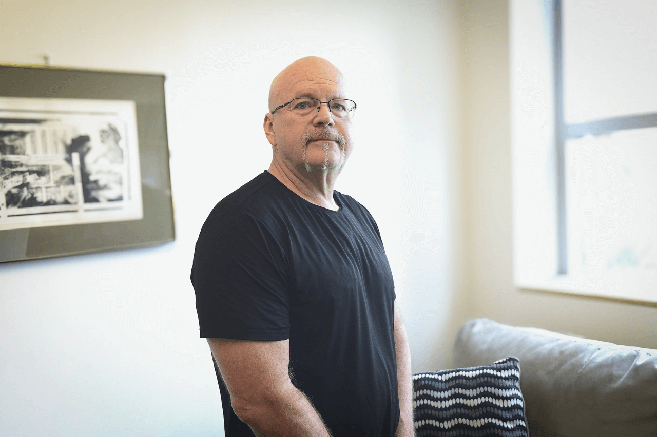 Man in black t-shirt with a goatee in a conference room