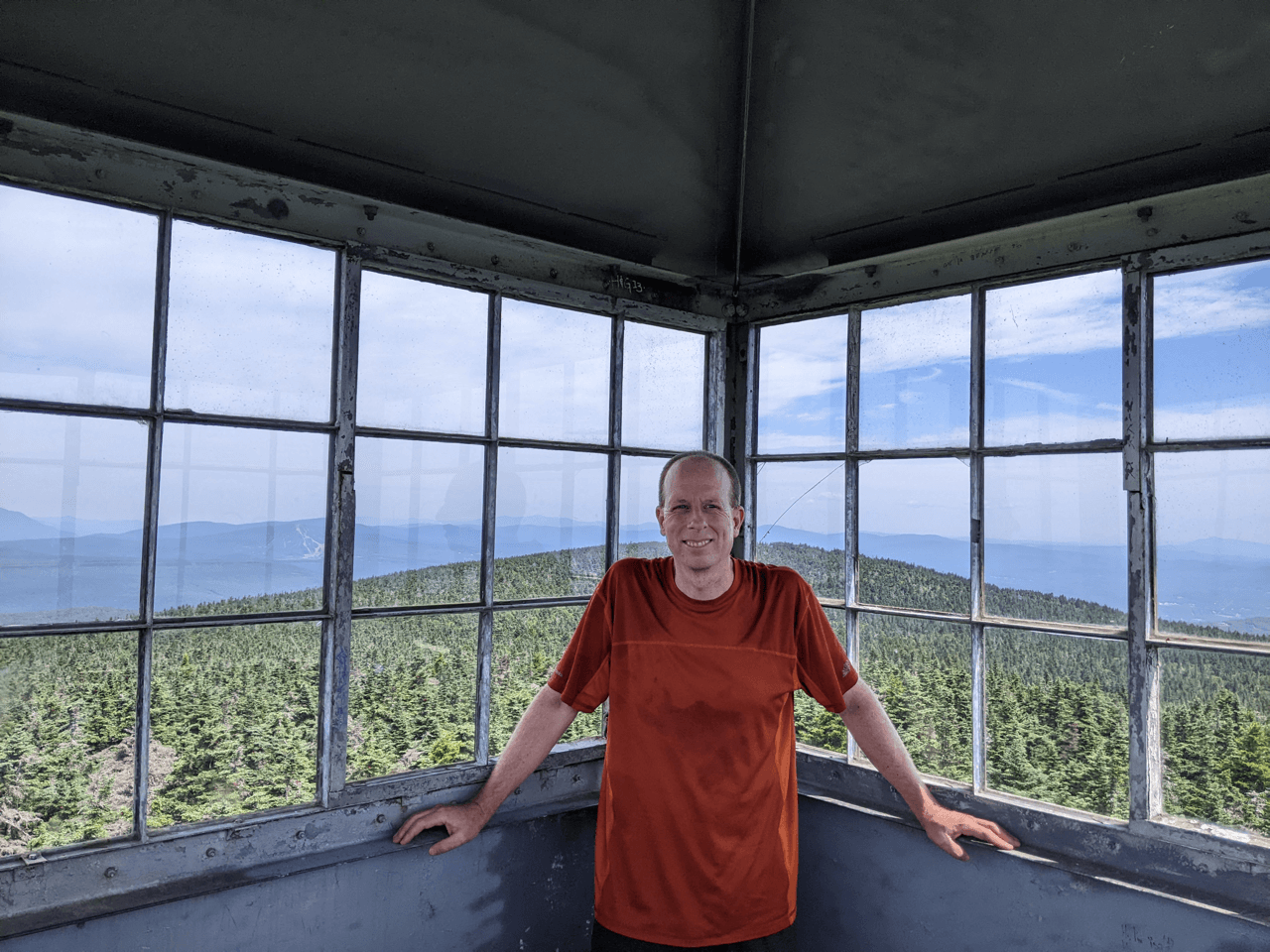 Man standing inside a fire tower on a mountain