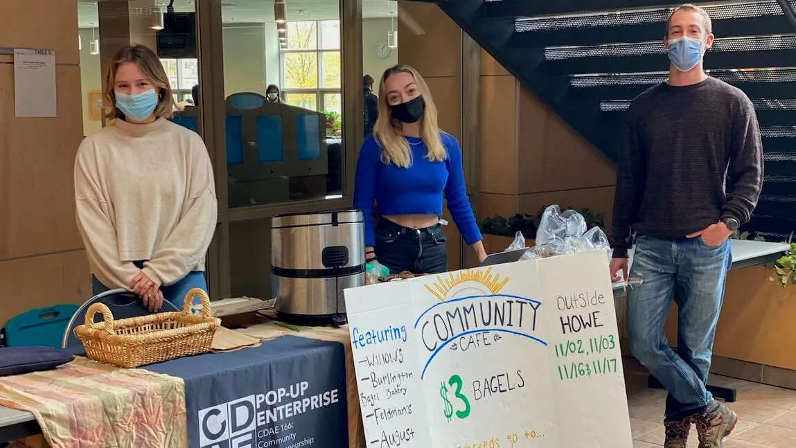 students standing in front of a table selling bagels