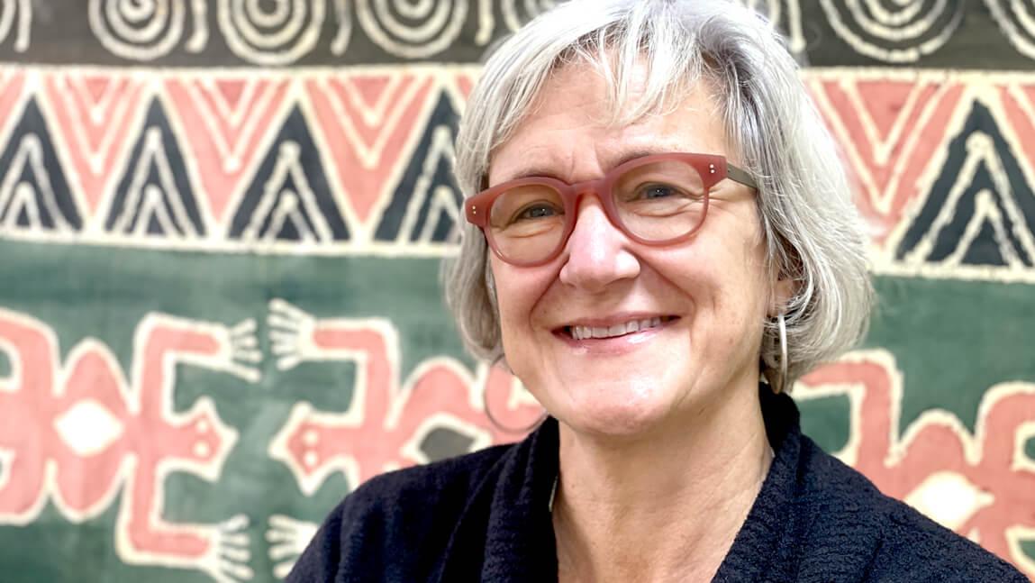 profile photo of Polly Ericksen standing in front of a patterned backdrop.