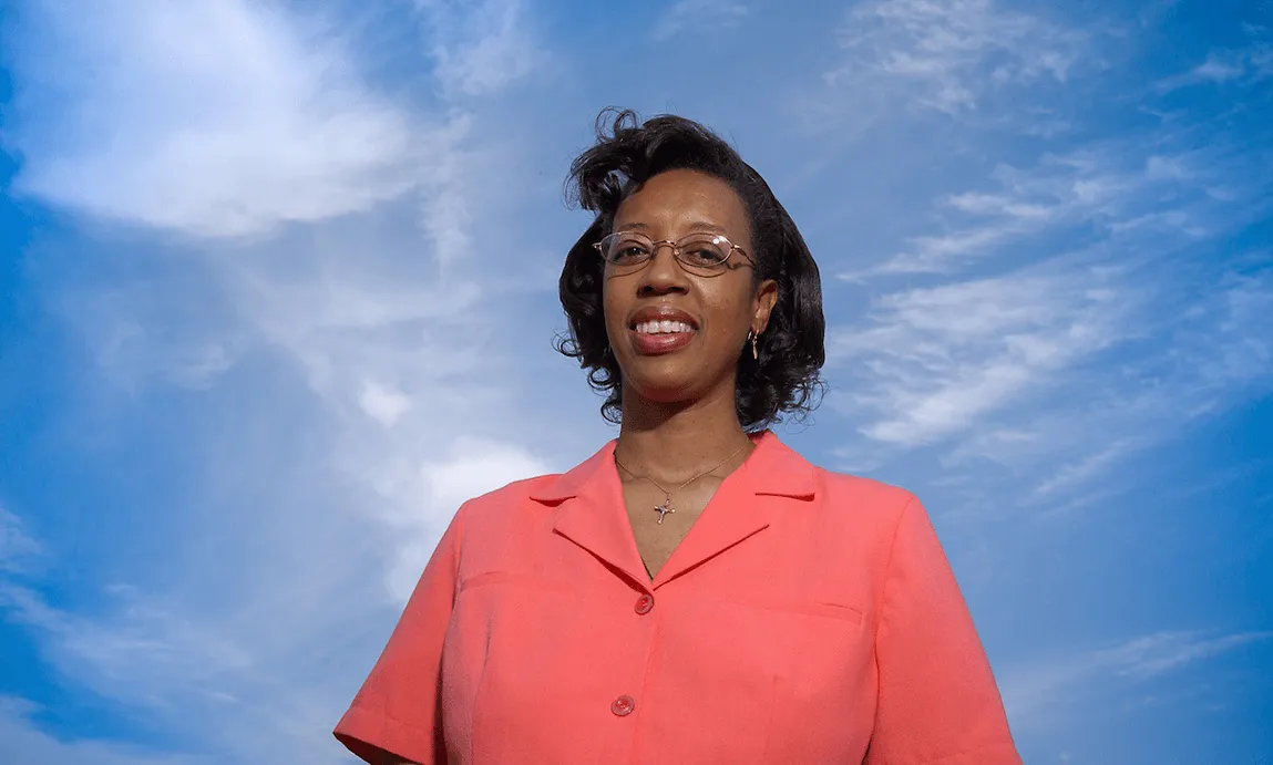 Lesley-Ann in bright coral colored blouse against blue skies