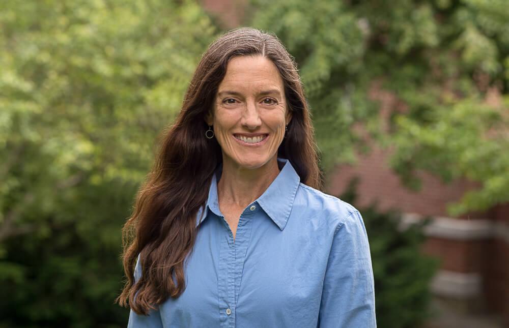 Alice Fothergill, UVM Professor of Sociology in foreground with trees and shrubs in background