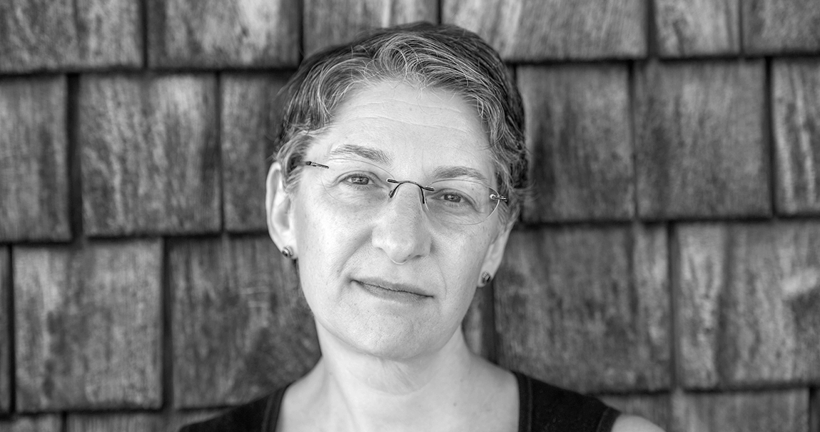 Black and white headshot of Felicia, somber look, against clapboard siding