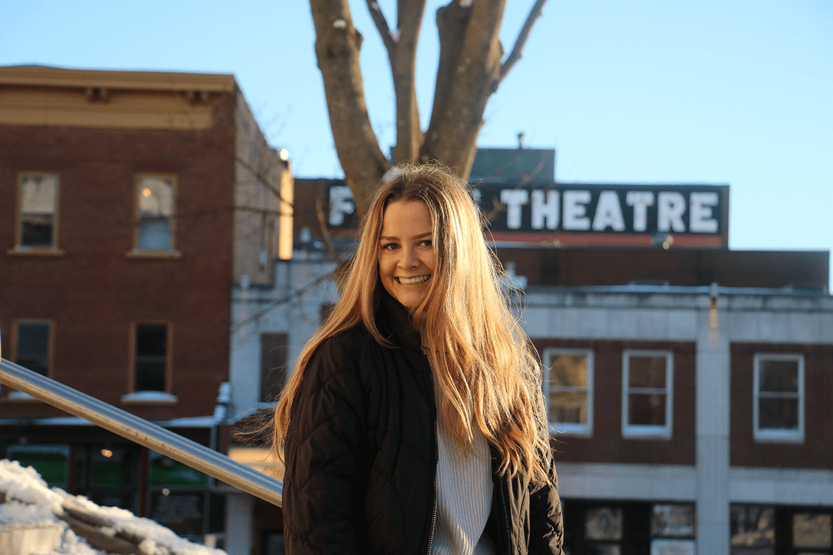 Sarah Blow in front of row of buildings
