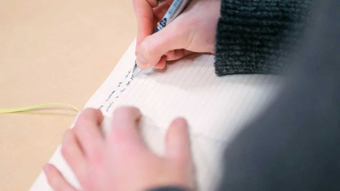 a hand holding a pen over a notebook