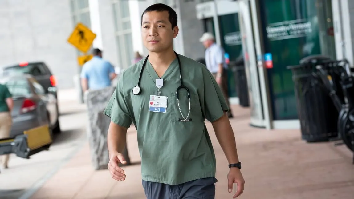 Nurse walking in front of UVM Medical Center entry