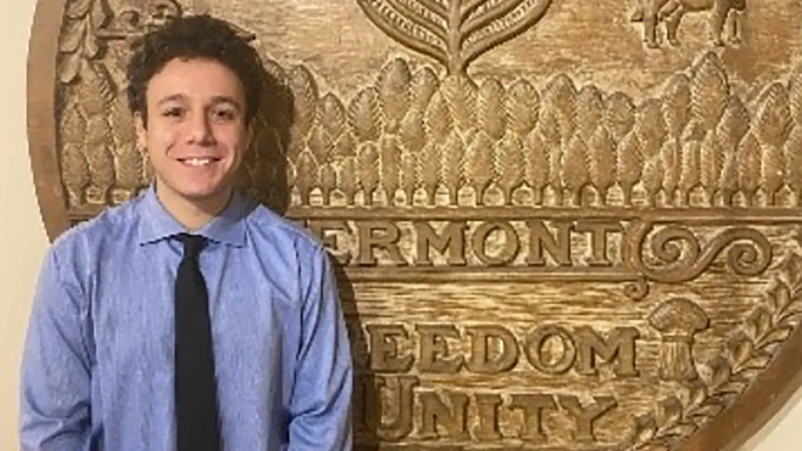 A young person standing in front of a plaque