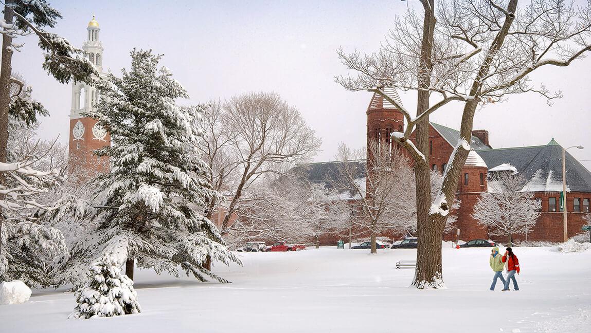 two students walking across snowy campus green
