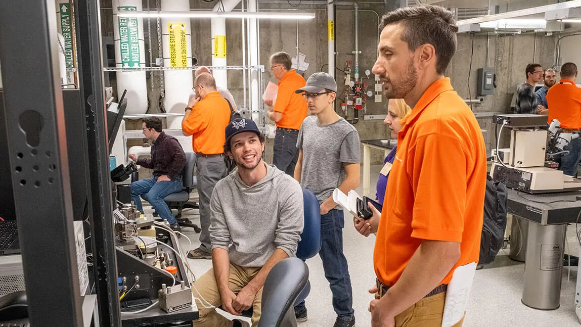 UVM engineering student Ray Thibeault shares the device characterization teaching lab's wafer prober with visiting employees from GlobalFoundries. Photo: Chris Dissinger.