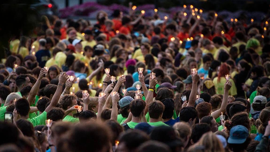 students holding lit candles at convocation ceremony
