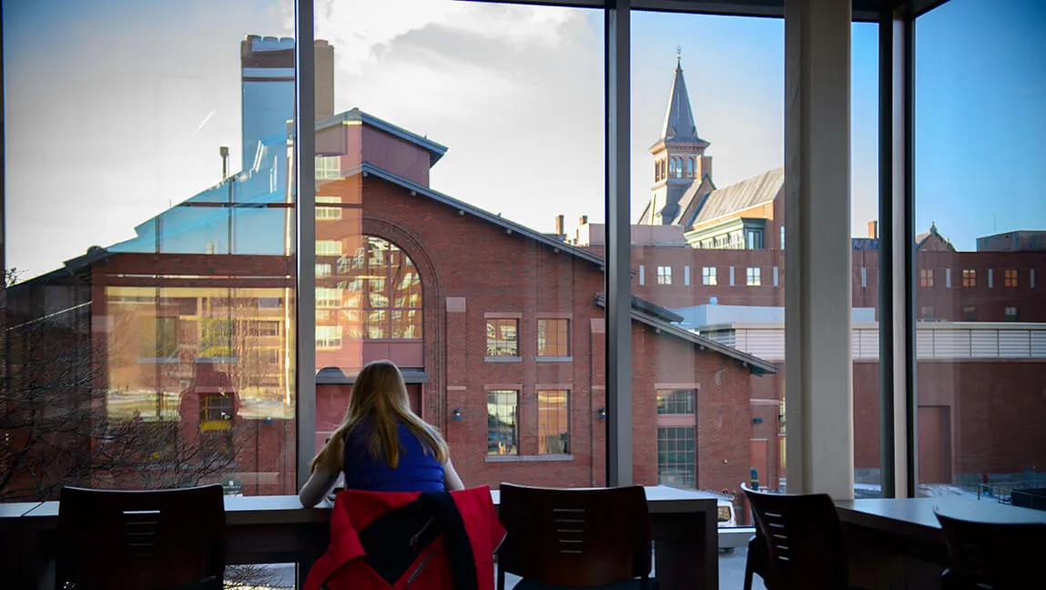 student at table inside looking out over campus