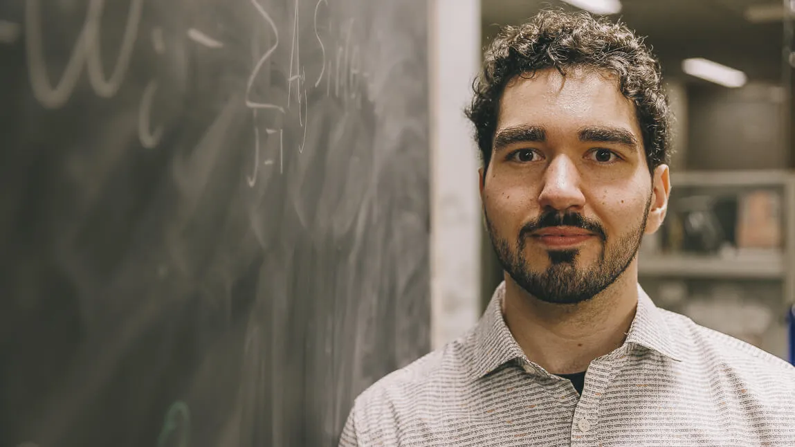Tobias Timofeyev next to a chalk board. 