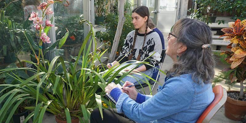 two women drawing a flower in a greenhouse