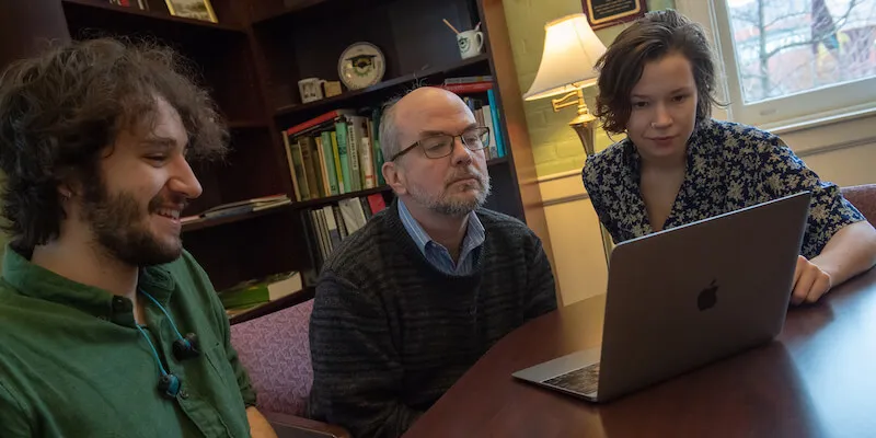students and professor sitting at a table