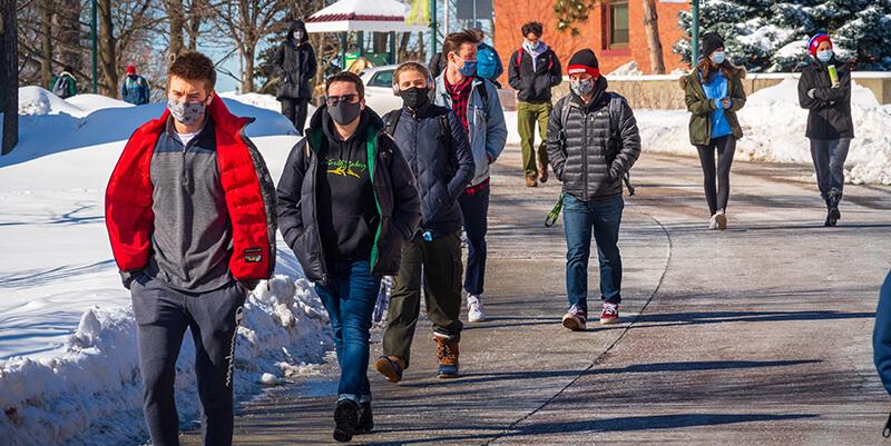 students wearing masks walking on campus in winter