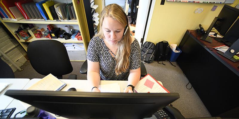 student on a phone call sitting at computer