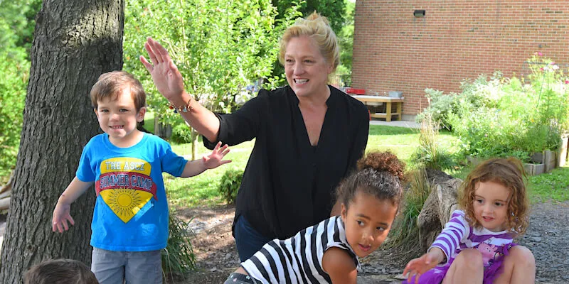 Barbara outside on playground with kids at UVM Campus Children's School