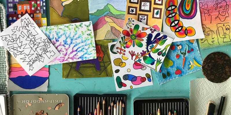 drawings and art supplies on a wooden table