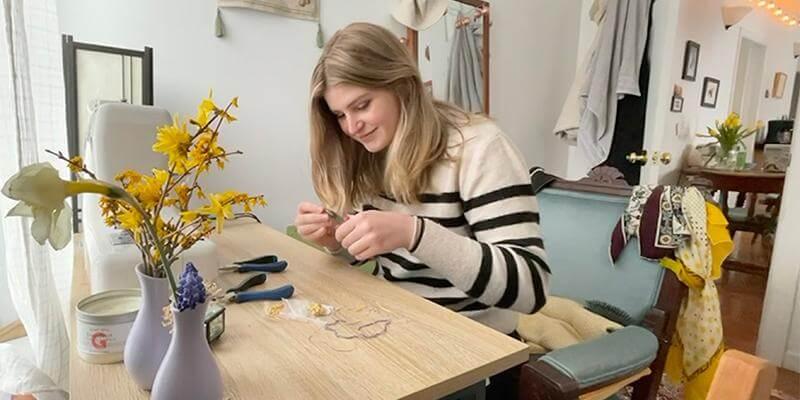 UVM student Ali Starkweather making jewelry on a table in her home.