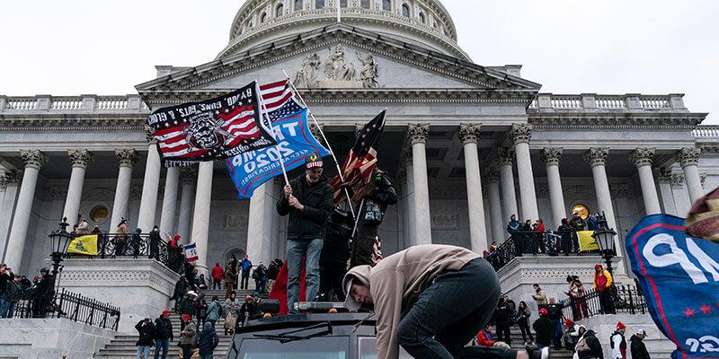 Protestors storm the U.S. Capitol Building, waving flags for Donald Trump