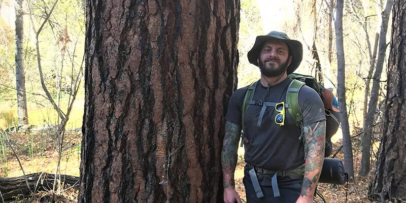 Jordan Luff stands next to ponderosa pine