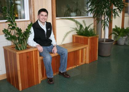 Matthew Durfee (PRT '12) and his custom built planter box-bench made from reclaimed Aiken Center furniture