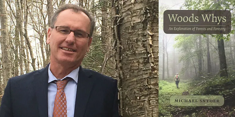 Michael Snyder leans against a yellow birch in the woods and his new book