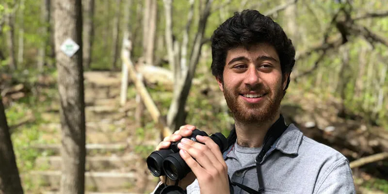 Mike Perrin holds binoculars at a natural area