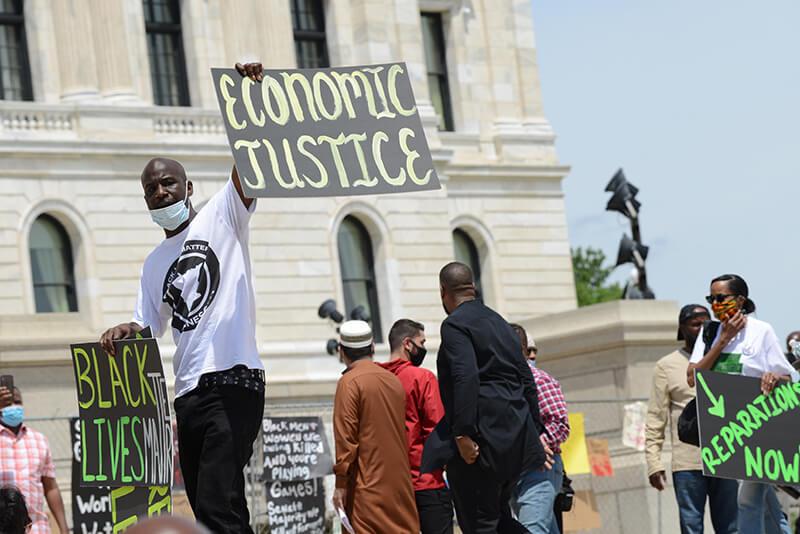 Protestor holds “Economic Justice” sign at protest for reparations in Minneapolis capitol building. 
