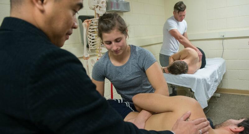 Professor Escorpizo working with students in physical therapy lab.
