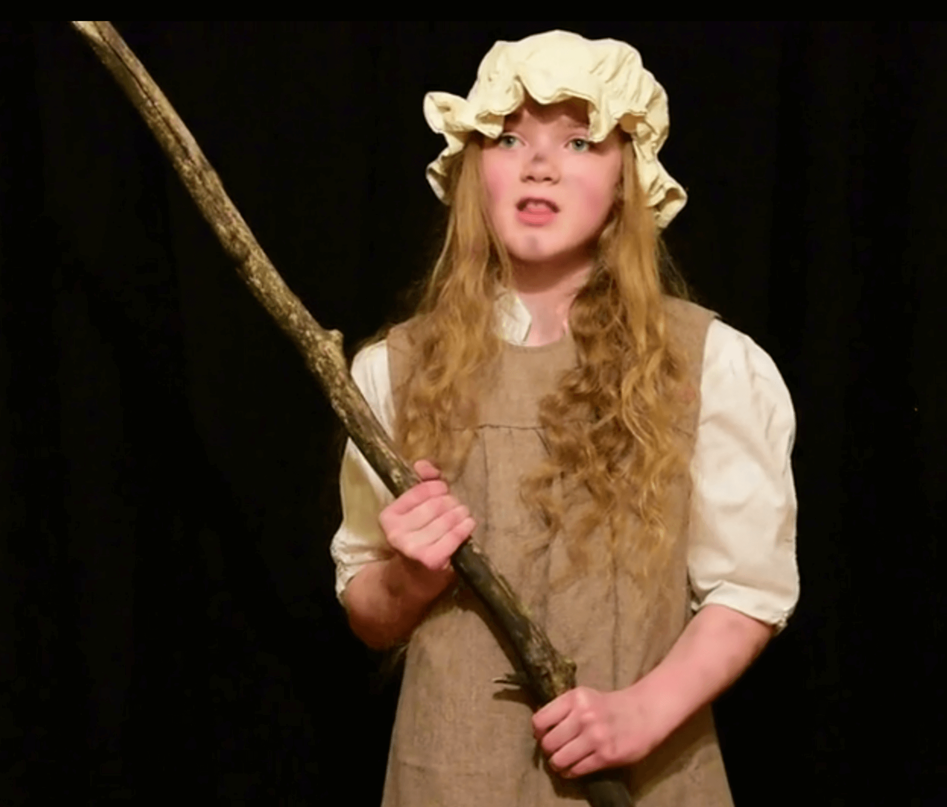 Pittsford 4-H'er Adeline White singing "Castle on a Cloud" while wearing a potato sack, a bonnet, and holding a stick