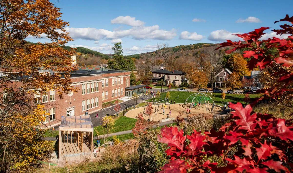 Union Elementary School Playground. A brick building surrounded by fall leaves with playground equipment