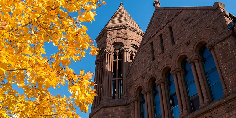 A tree with yellow leaves stands in front of UVM's Billings Library