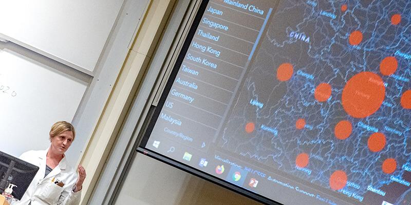 UVM researcher stands in front of map of coronavirus outbreak
