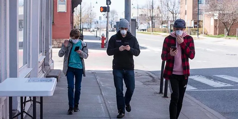 Three people walking down a Burlington street wearing face masks. 