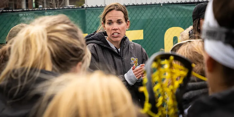 Women's lacrosse coach Sarah Dalton talks to University of Vermont student athletes