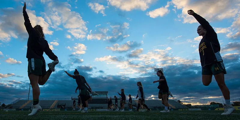 Women's lacrosse warms up at Virtue Field at dawn